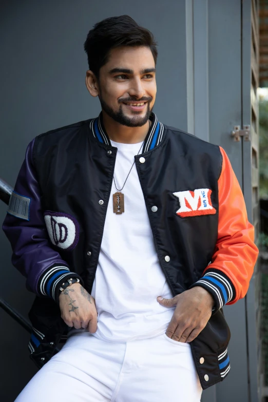 a man wearing a baseball jacket and white pants with a baseball bat in his hand