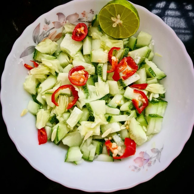 a plate with cucumbers, tomatoes, and other foods