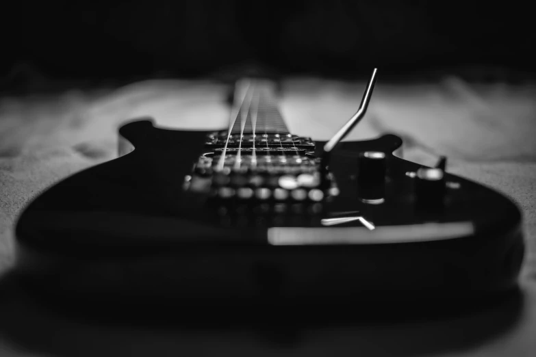 the strings on a black guitar are shallow focus