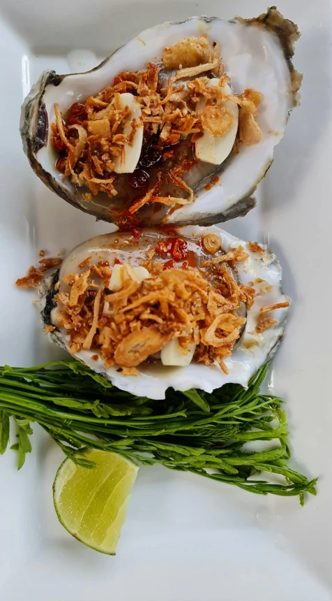 three opened oysters with garnish and sauce on top