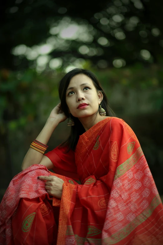 woman in red sari with a large tree background
