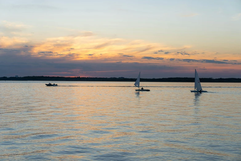 two boats sailing in the water during sunset