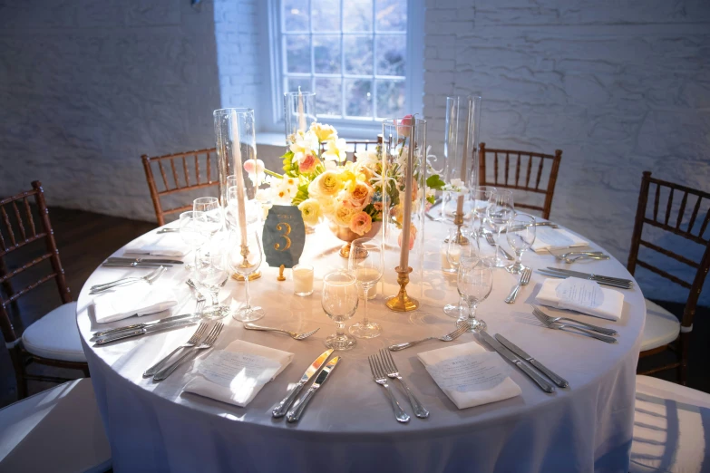 a close - up of a round table with several place settings and flowers