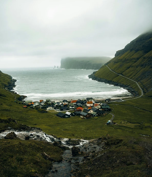 a rural land area on the edge of an ocean with hills in the background