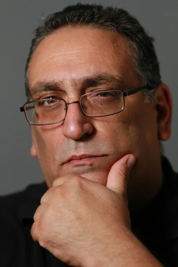 a close up of a person wearing glasses and posing for the camera