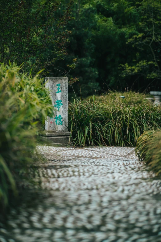 a very big lush green park with a big stone pillar