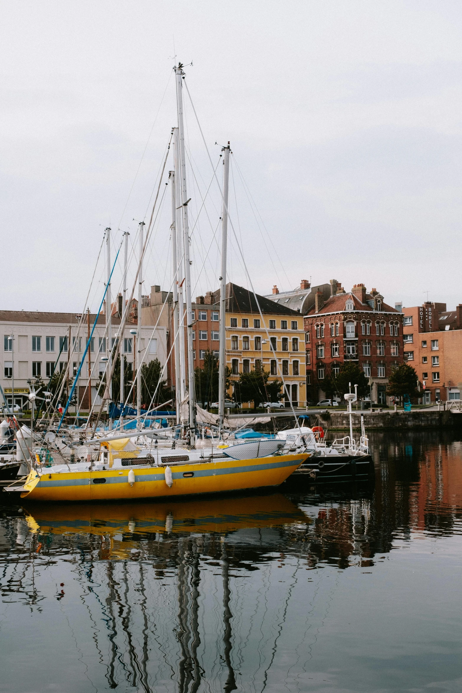 a yellow sailboat docked at the dock of a harbor