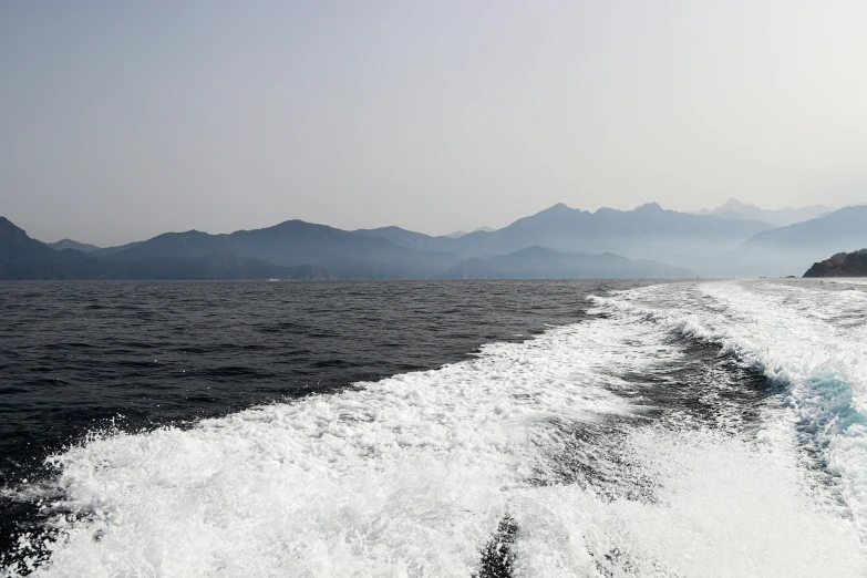 a boat is going down the ocean with mountains in the background