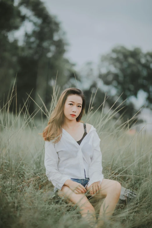 young woman sitting on the grass in a field