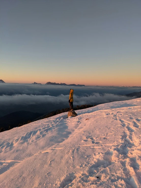 person standing on top of snow covered slope at dusk