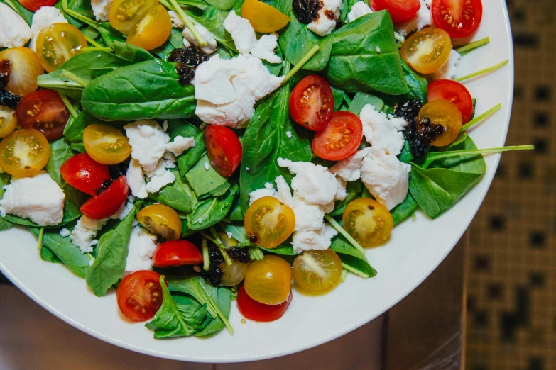 a plate of chopped tomatoes, mozzarella, spinach leaves and cheese