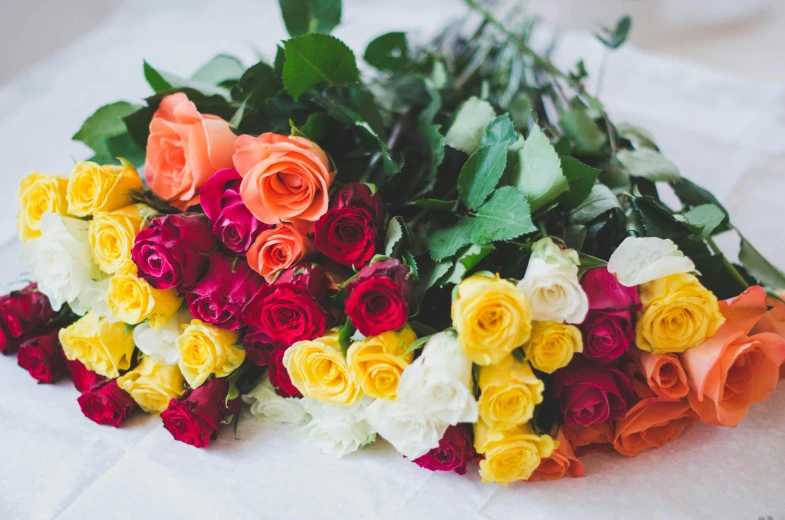 a large bouquet of flowers laying on top of white sheets