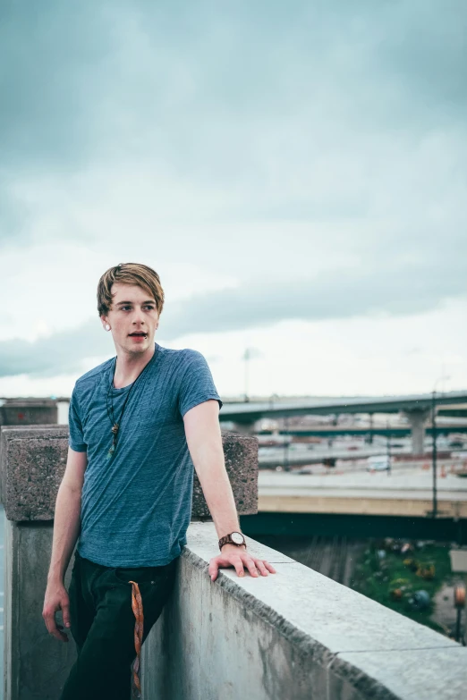 a boy leaning on the top of a bridge