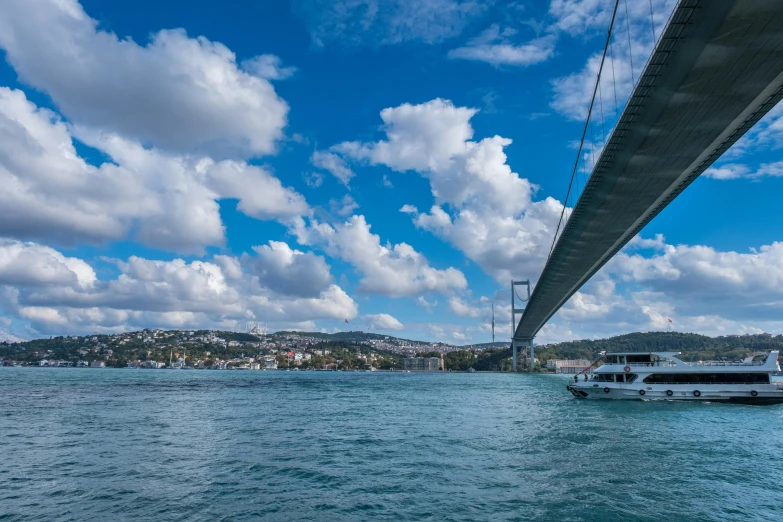 two boats are floating in the water by a large bridge