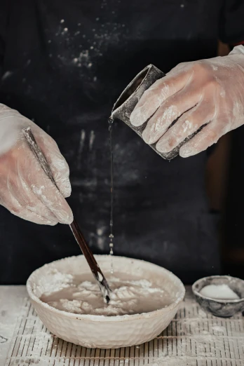 a person in gloves washing their hands in a bowl