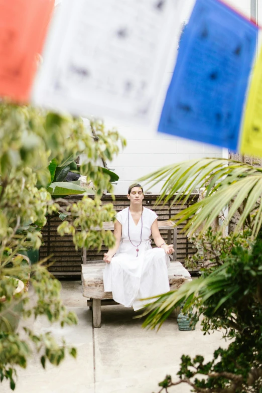 a person sitting on top of a wooden bench near flags