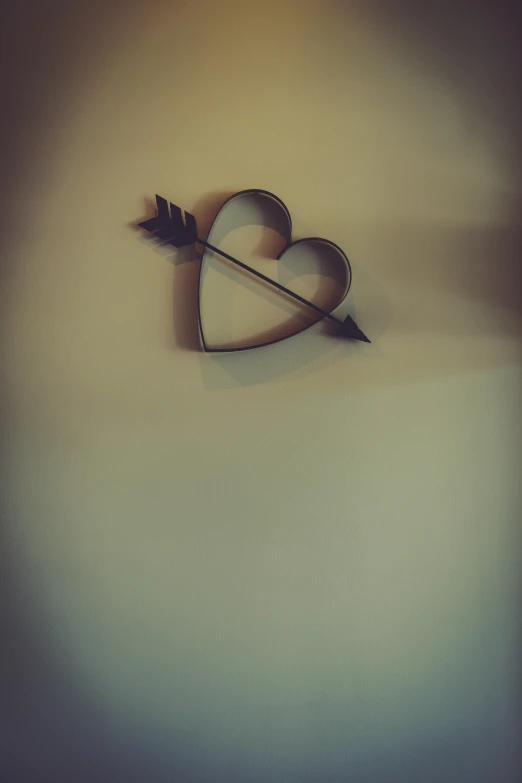 a paper arrow is shown stuck in a heart shape