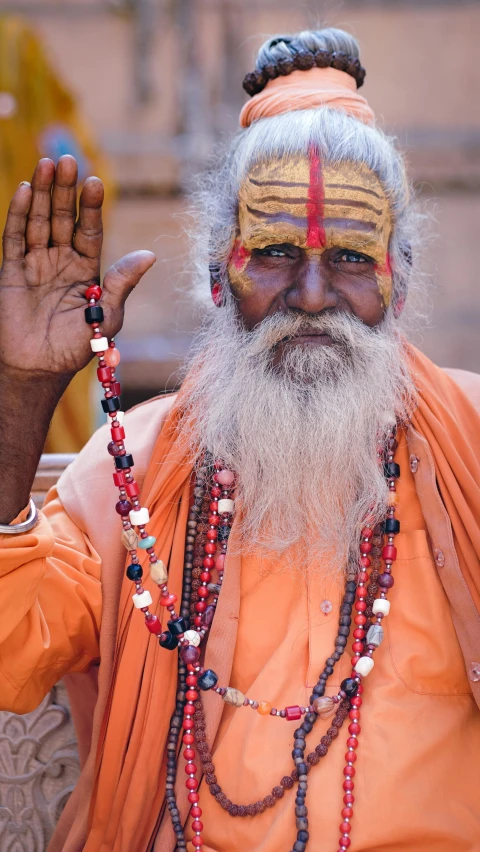 an old indian man in orange attire and head jewels