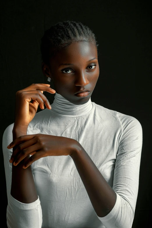 a black woman sitting against a black backdrop