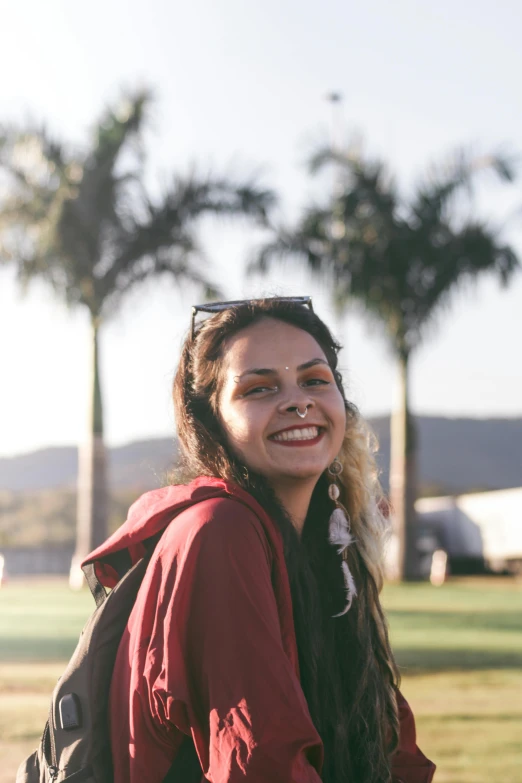 a woman wearing a backpack, smiling for the camera