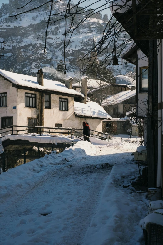 snow covered road with homes and mountains in background