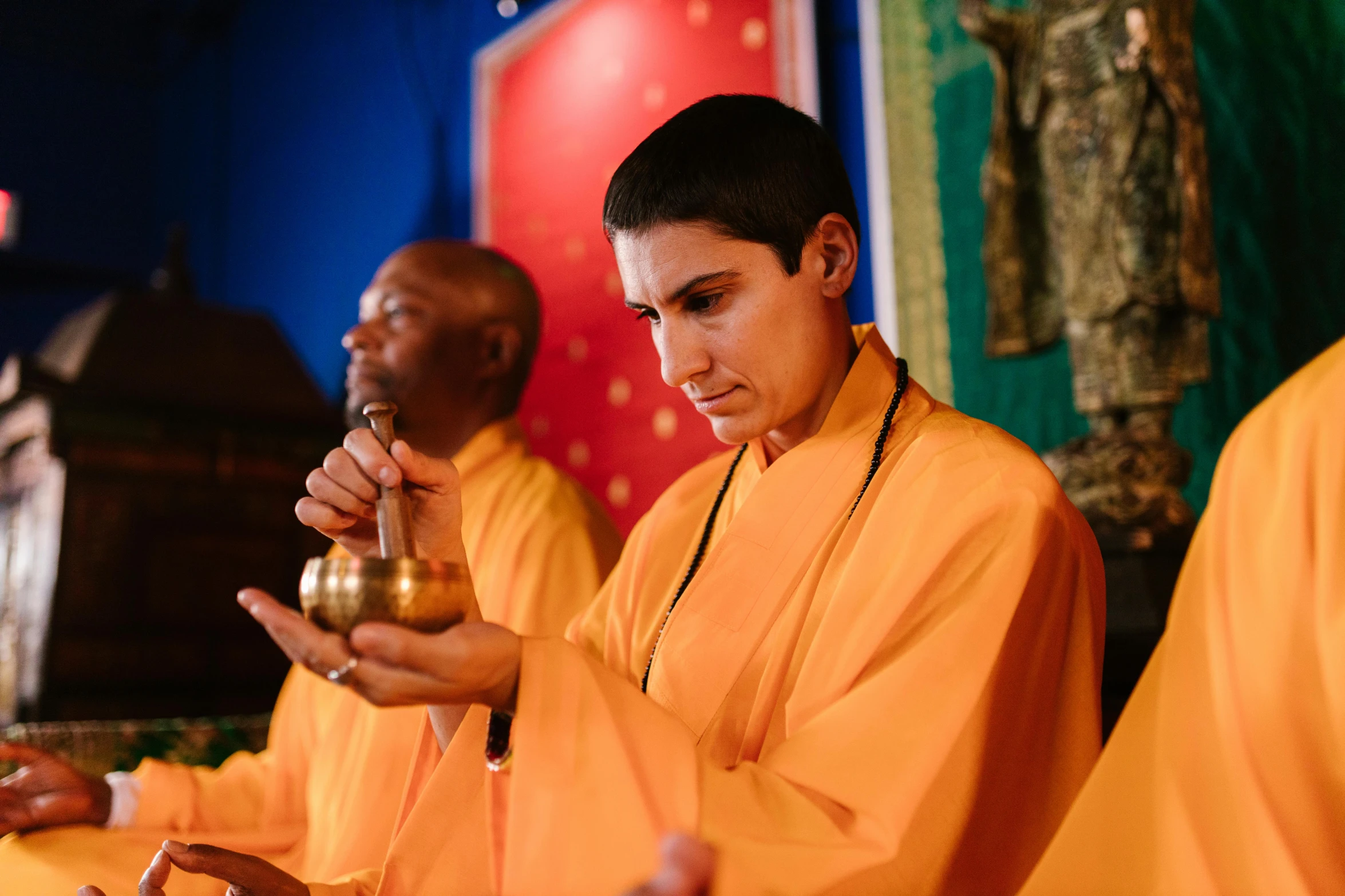 three men in orange robes holding golden balls