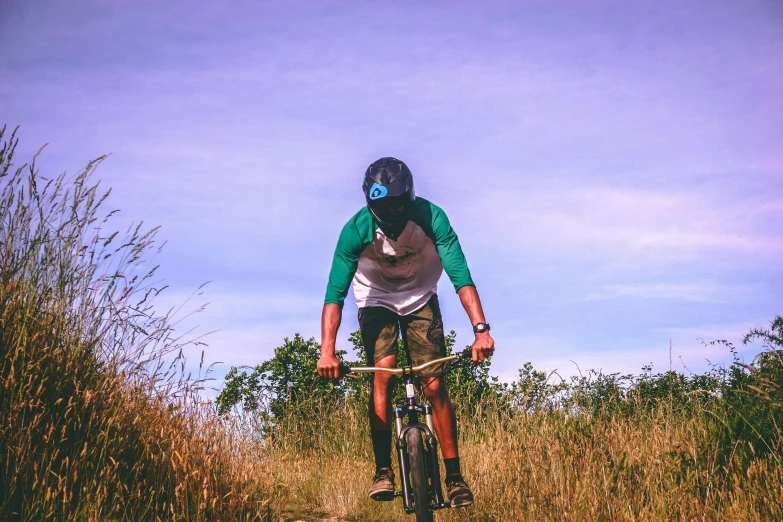 man riding mountain bike down hill through brush