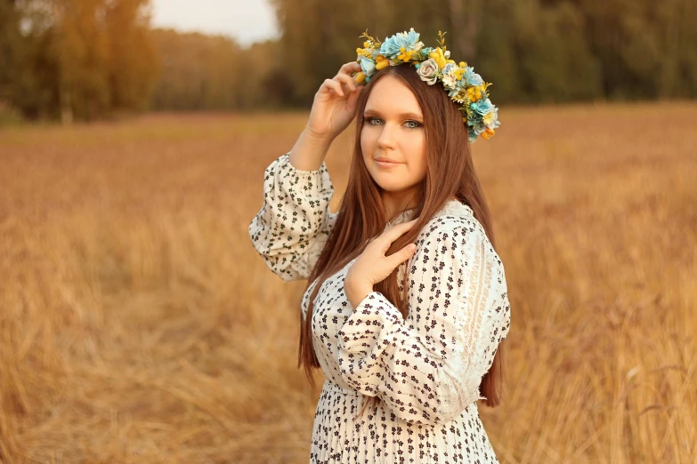 a woman in a white dress stands in a field with dried grass