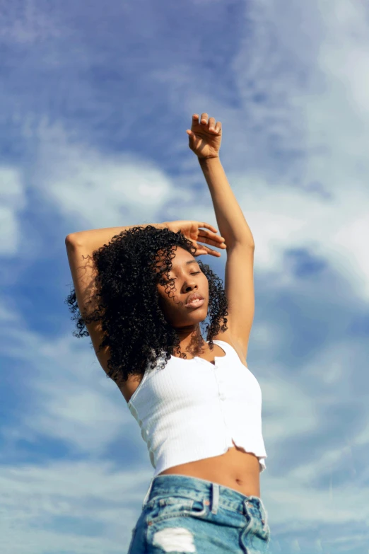 a woman standing in the sun with her arms outstretched