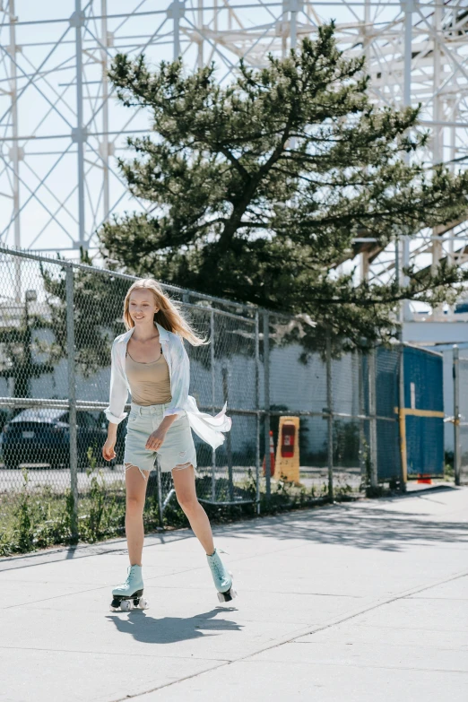 a girl skateboarding along the concrete near a fence