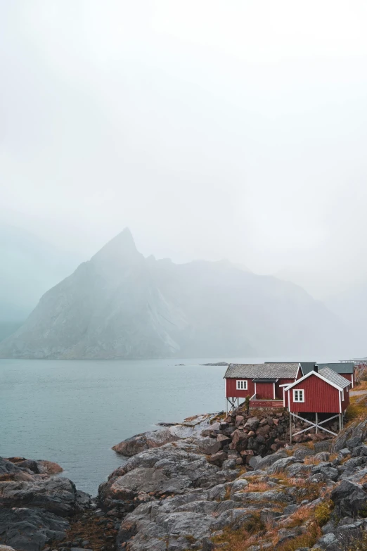 a view from the shore of a mountain lake that has red houses