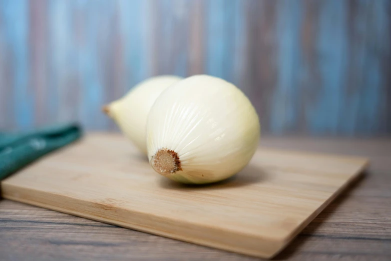 a wooden  board with two onions sitting next to each other