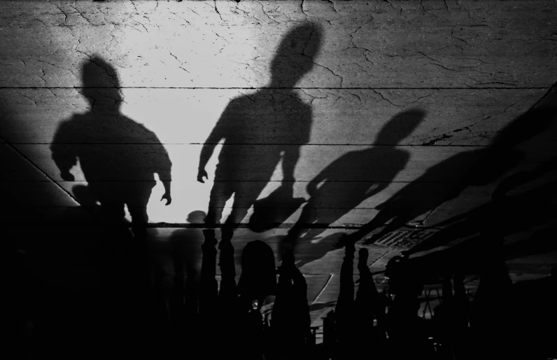 three people are casting shadows against the wooden wall