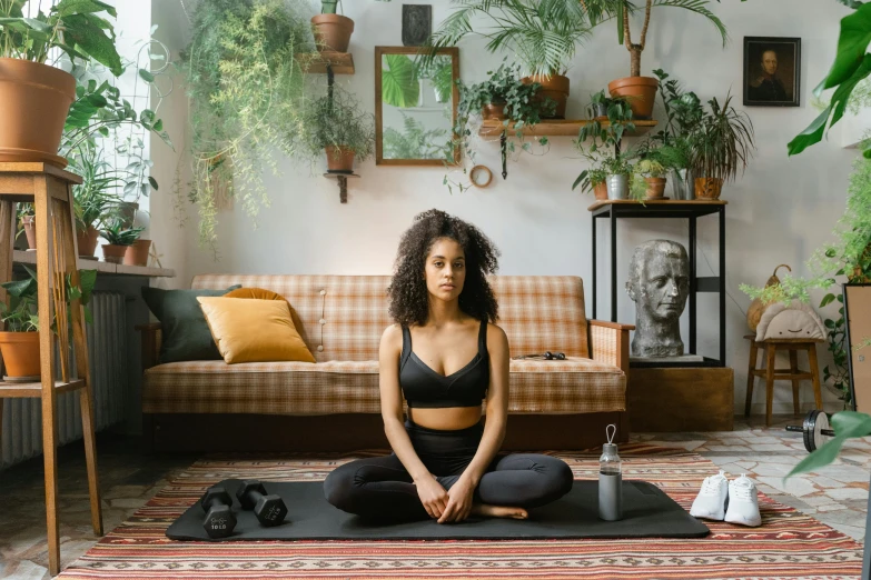 a woman sitting in yoga pose in front of a couch