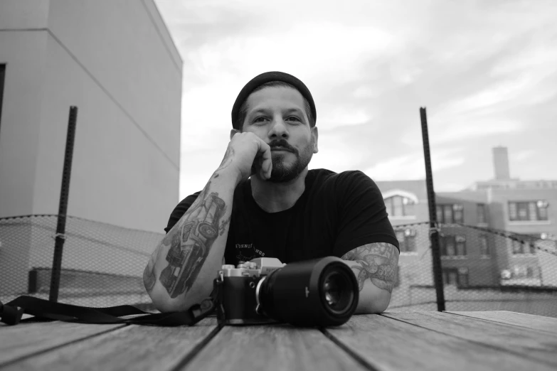 a hipster sitting at a table with his hand in his mouth