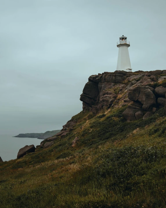 a lighthouse sitting on a rocky cliff side next to the ocean