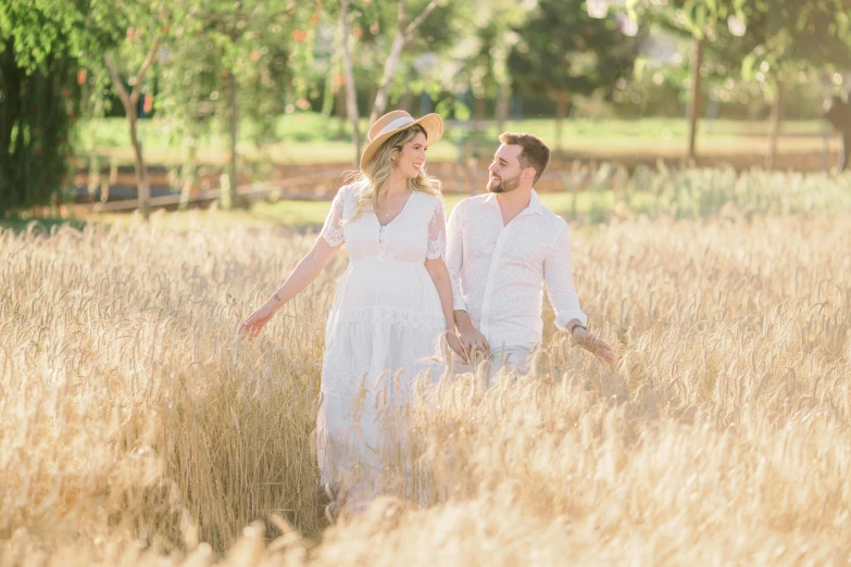 a man and woman standing in a field of tall grass