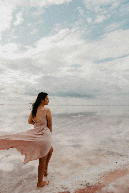 a woman is standing in the sand on a beach