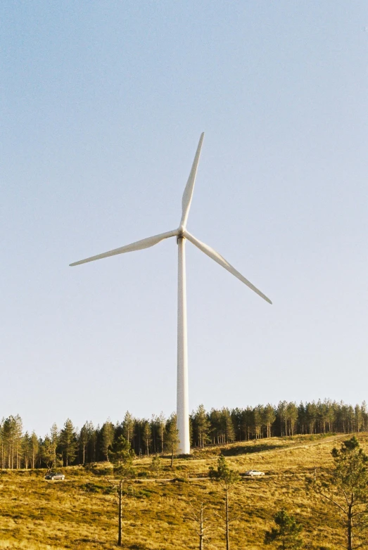 a windmill on top of a hill with grass and trees