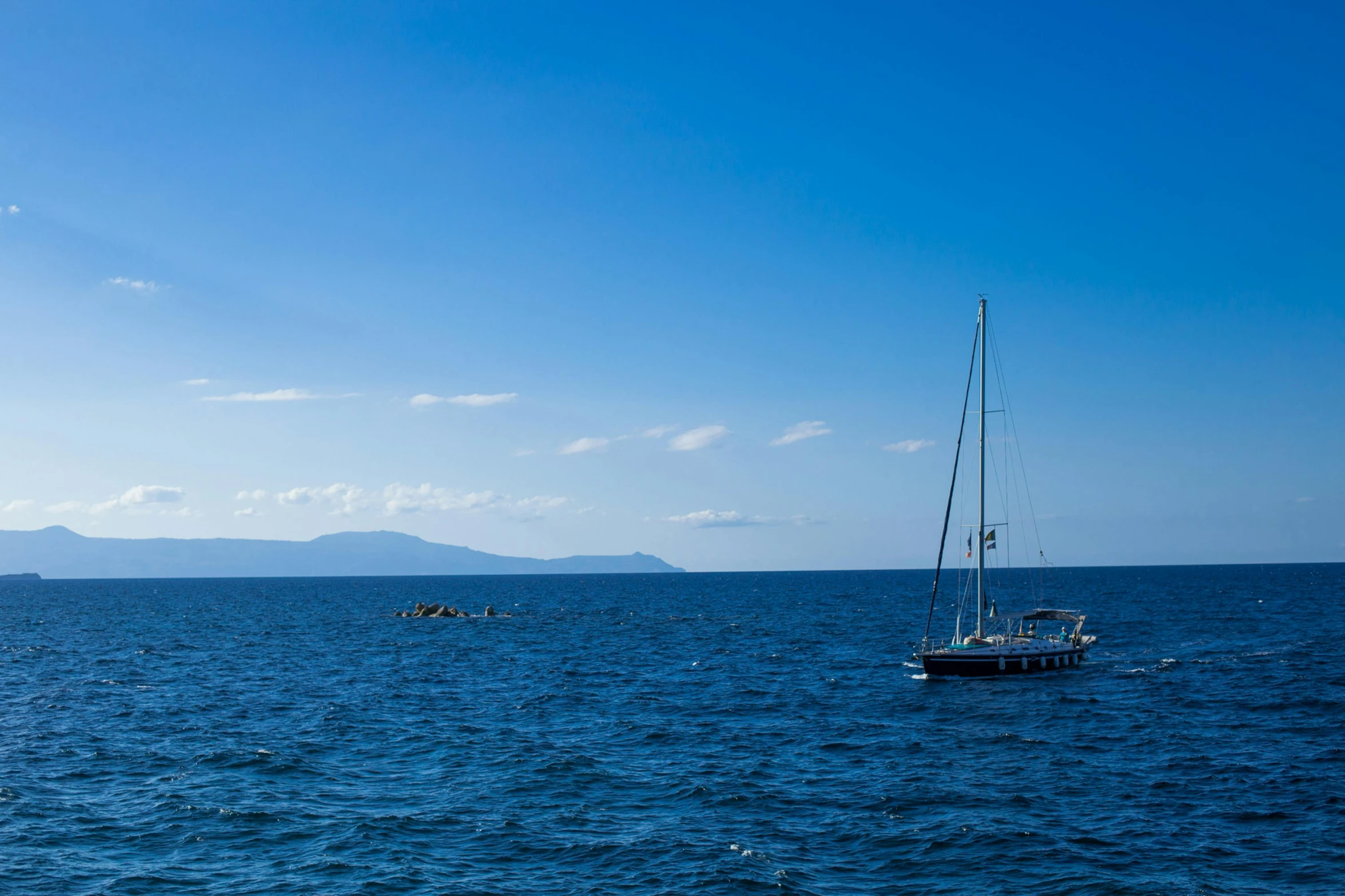 the ocean has a boat on it with two small people in it