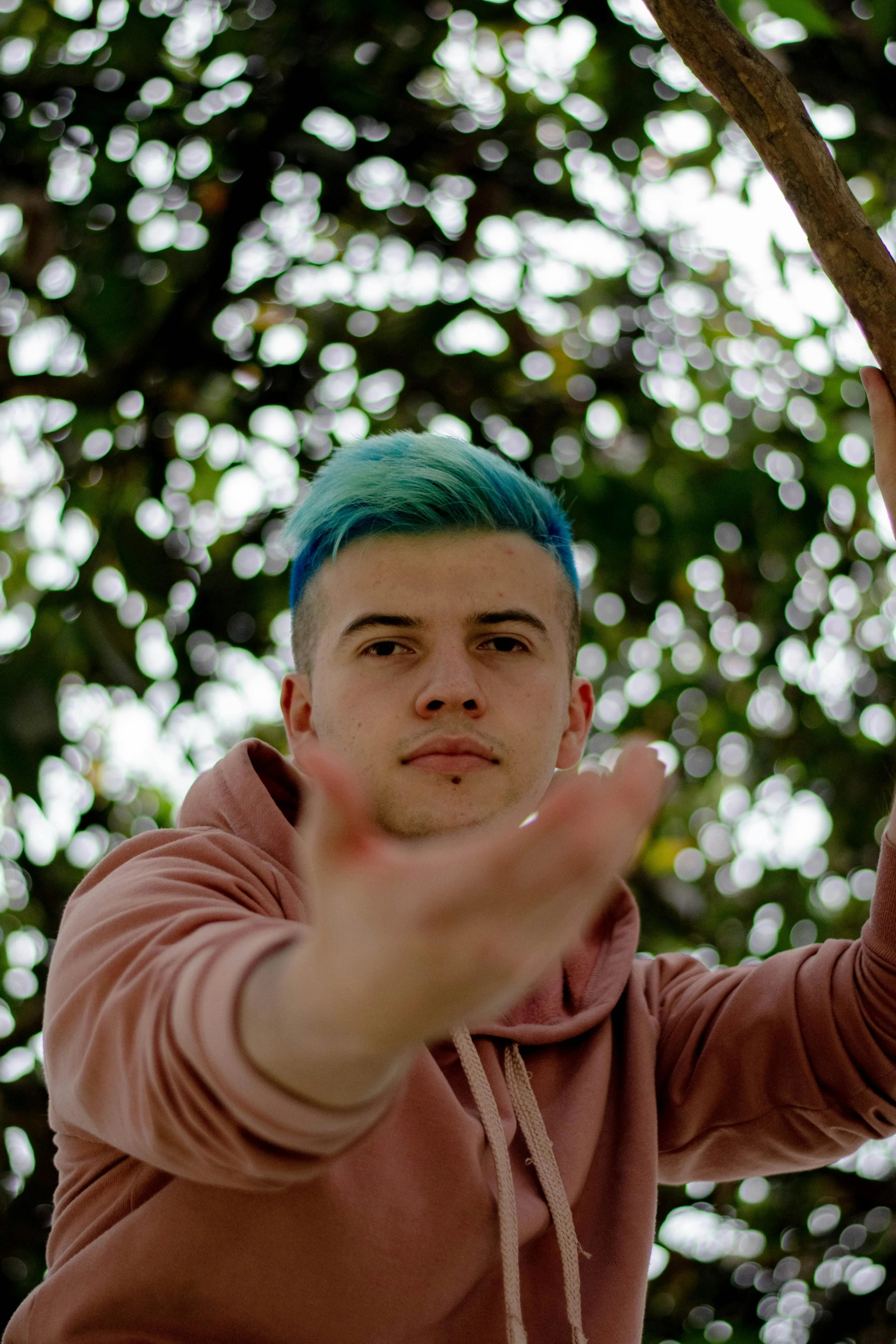 a man standing outside with green hair and gesturing