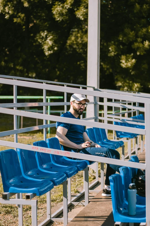 a man wearing a face mask while sitting on a blue bench