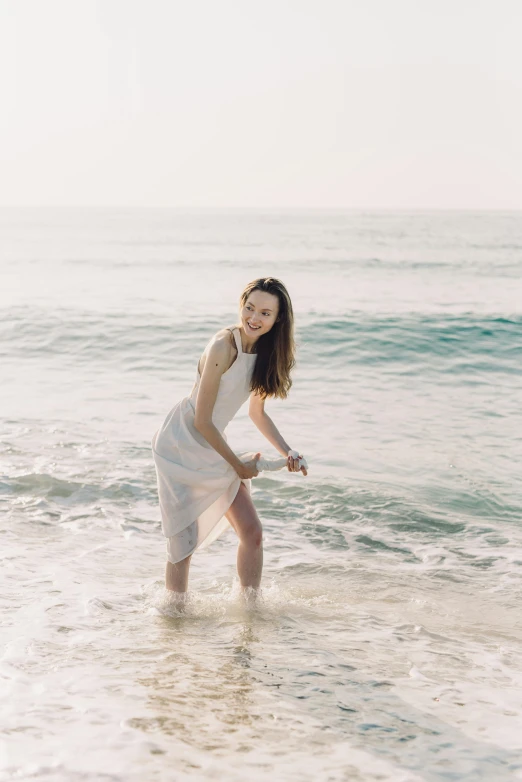 woman in dress walking into the surf at the beach