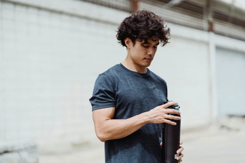 a man stands next to a building holding a beer bottle