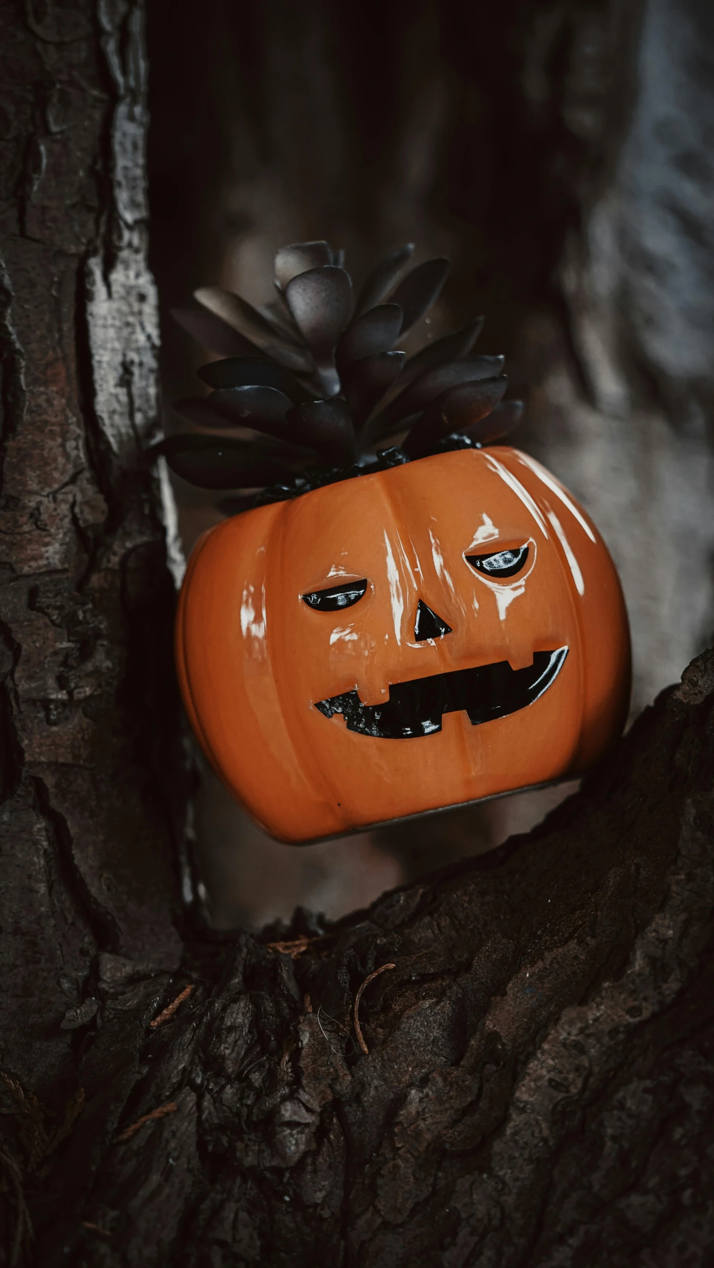 an orange pumpkin painted like a jack o lantern on tree nches