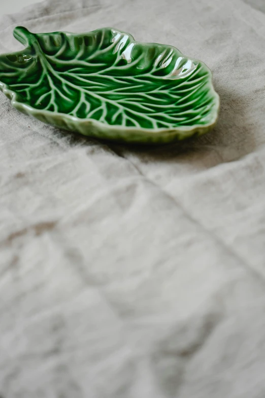 a leaf shaped ceramic bowl on a cloth