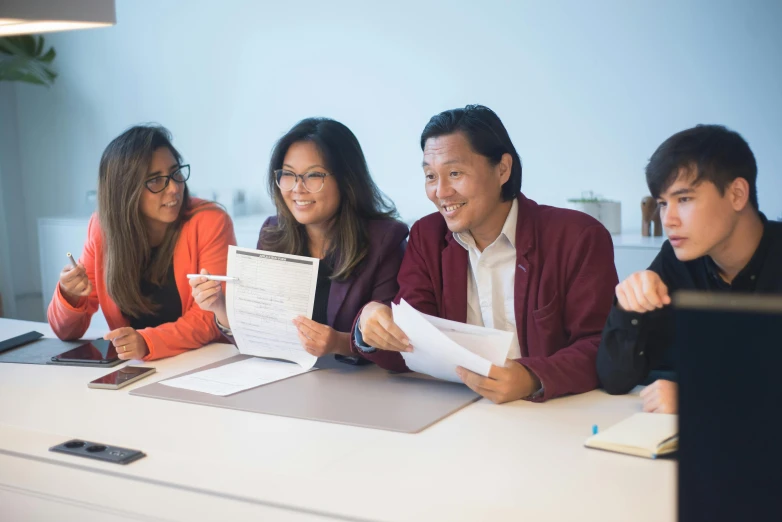 four people in an office looking at papers