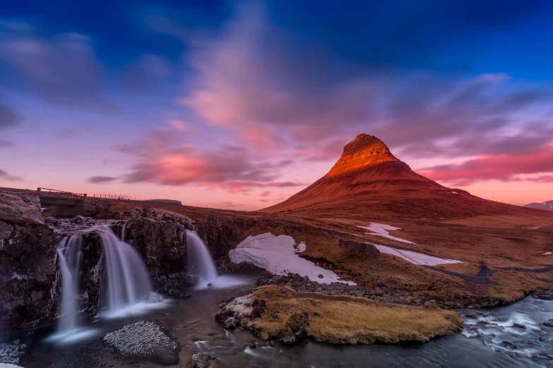 a sunset at the edge of the valley with a waterfall