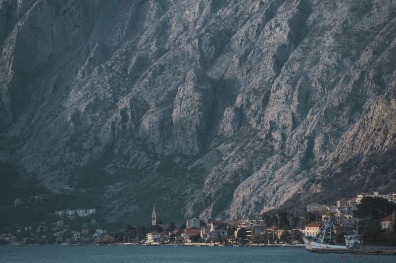 a body of water with some boats in it and a mountain covered city on the side