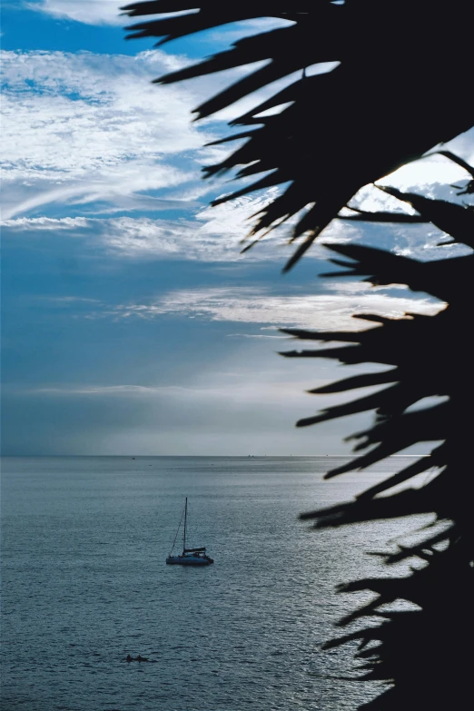 sailboat in open water at twilight with cloudy sky